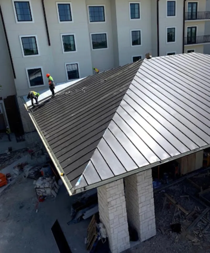 Crew installing standing seam metal roof panels on a commercial project in Red Hook